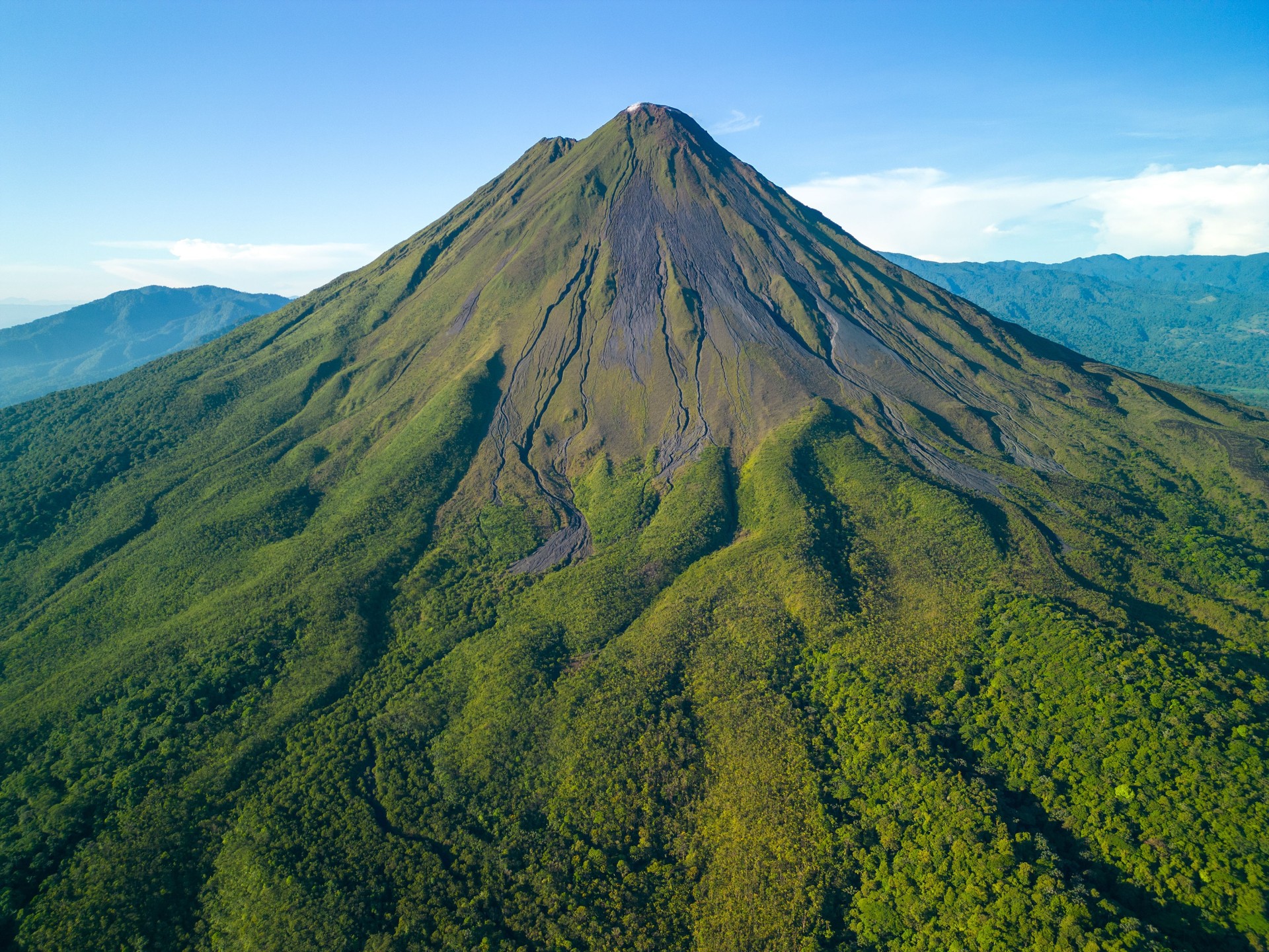 Scenic aerial view of Arenal Volcano in Costa Rica with lush green vegetation and clear blue sky